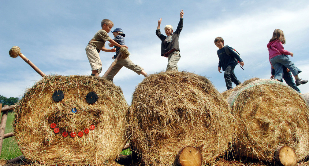 Kinder spielen und tollen auf einer aus Strohballen gebauten Raupe. (Bild: © dpa)