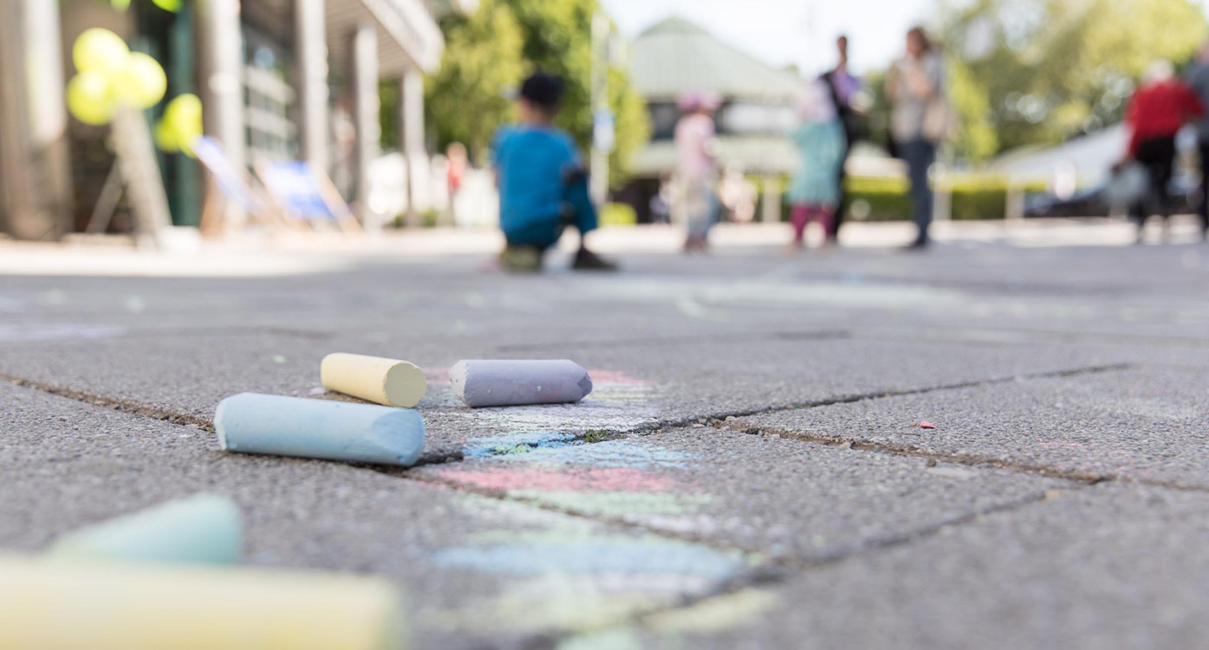 Kinder malen mit Kreide auf der Straße.']